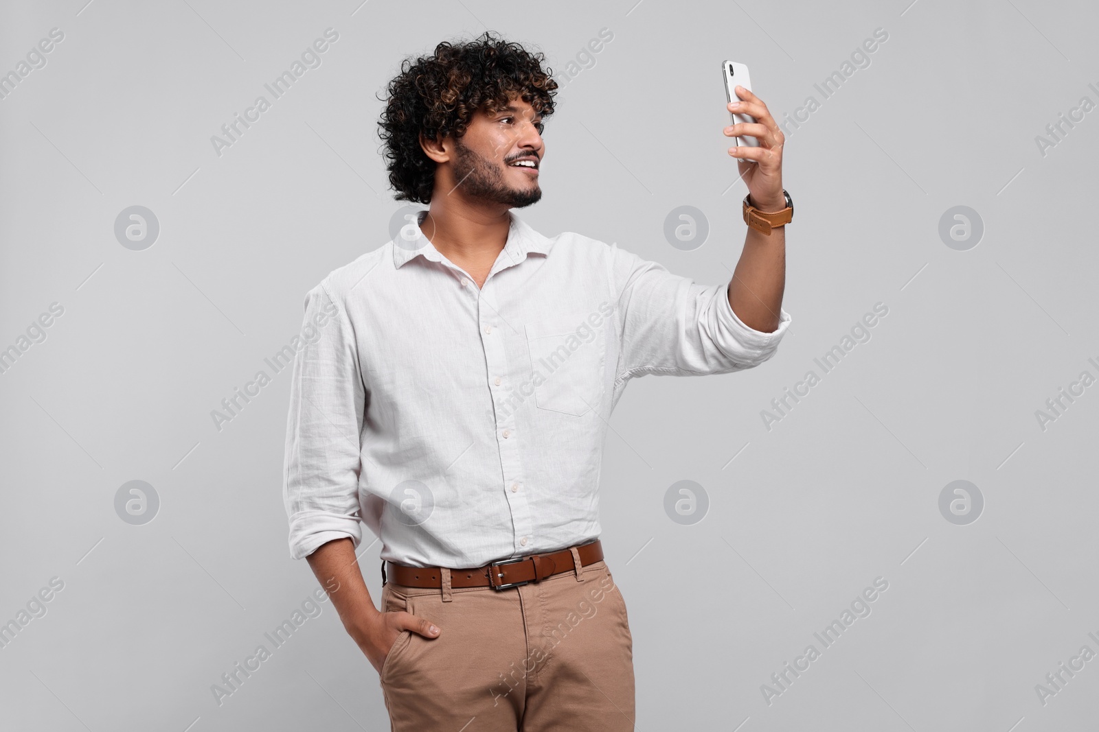 Photo of Handsome smiling man using smartphone on light grey background