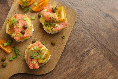 Photo of Tasty canapes with salmon served on wooden table, top view. Space for text
