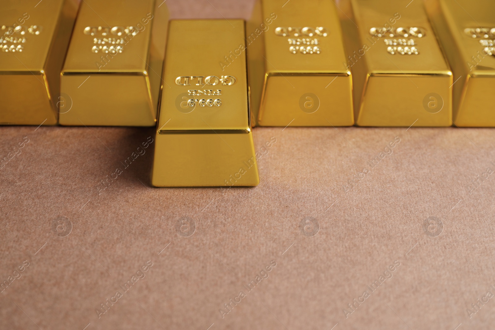 Photo of Many shiny gold bars on brown background
