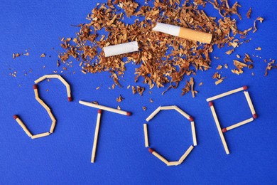 Photo of Word Stop made of matches, dry tobacco and broken cigarette on blue background, flat lay. Quitting smoking concept