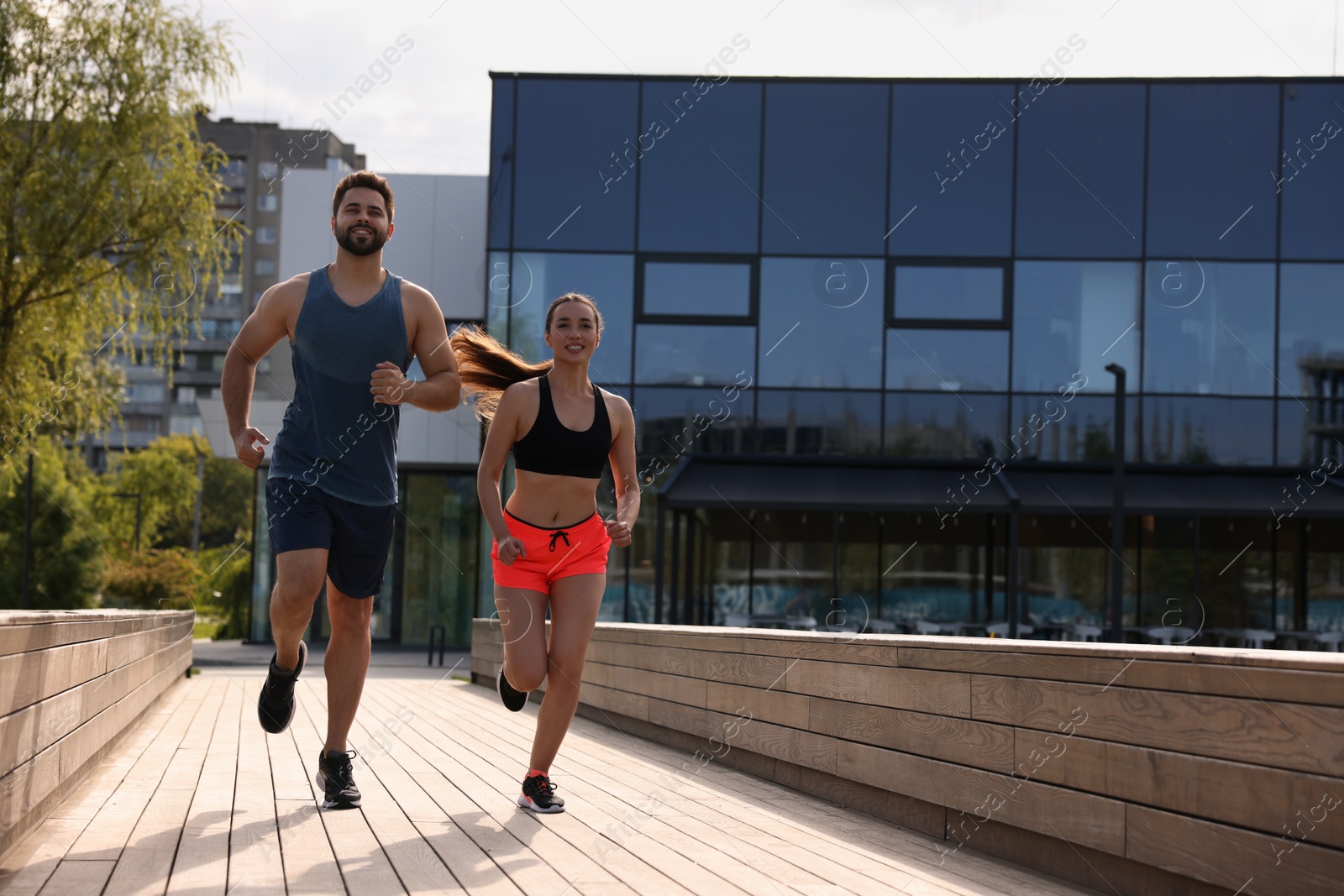 Photo of Healthy lifestyle. Happy couple running outdoors on sunny day, space for text