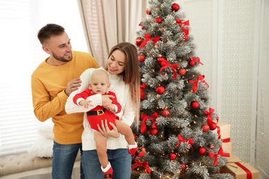 Photo of Happy family with cute baby near decorated Christmas tree at home