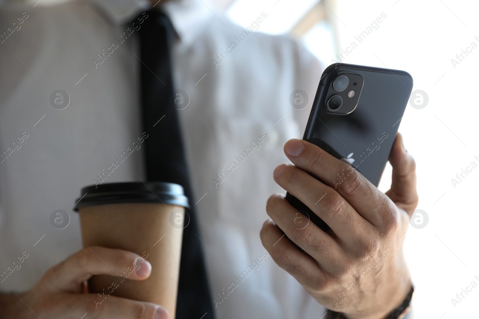 Photo of MYKOLAIV, UKRAINE - MARCH 16, 2020: Man holding iPhone 11 Black indoors, closeup