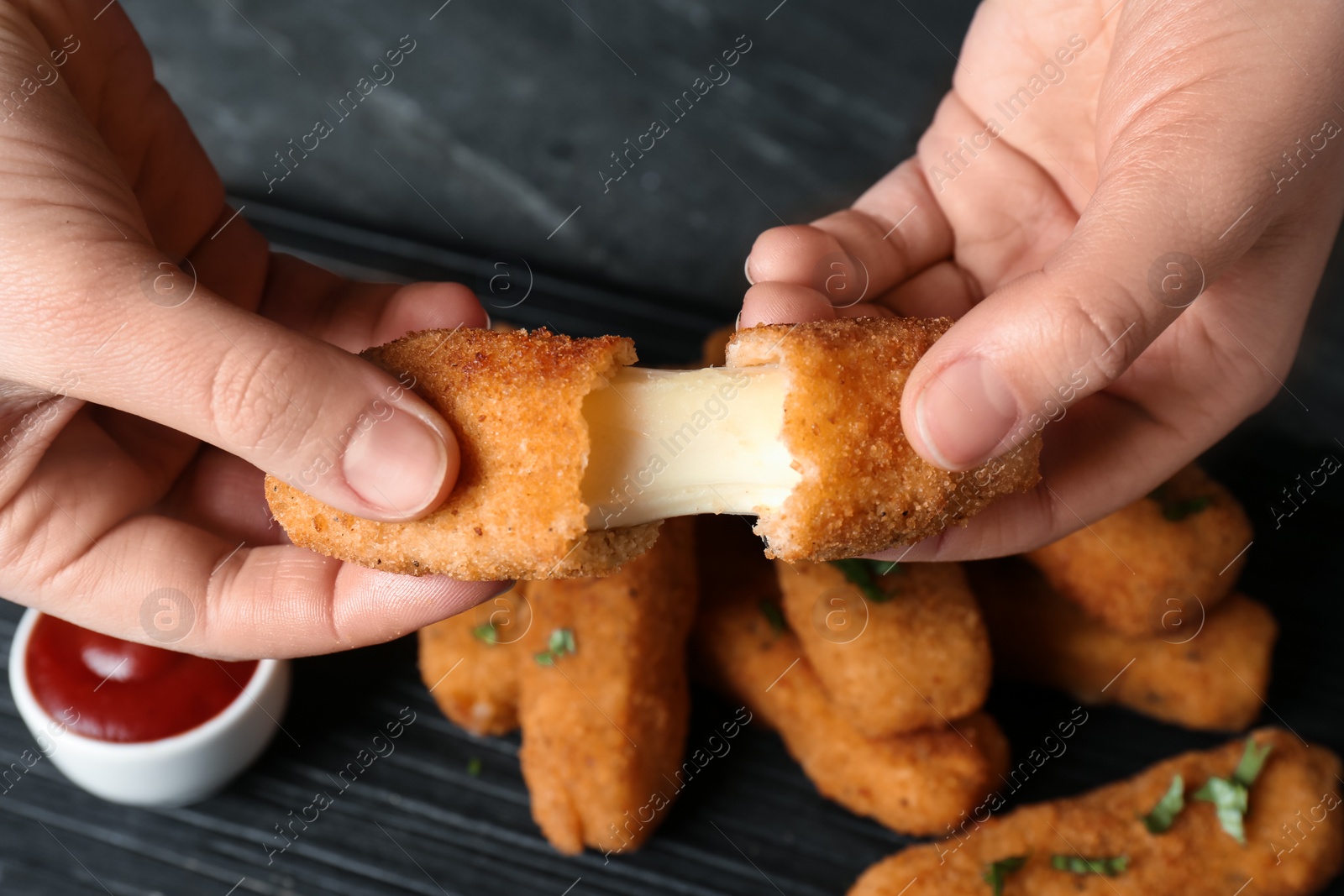 Photo of Woman holding broken cheese stick over table, top view