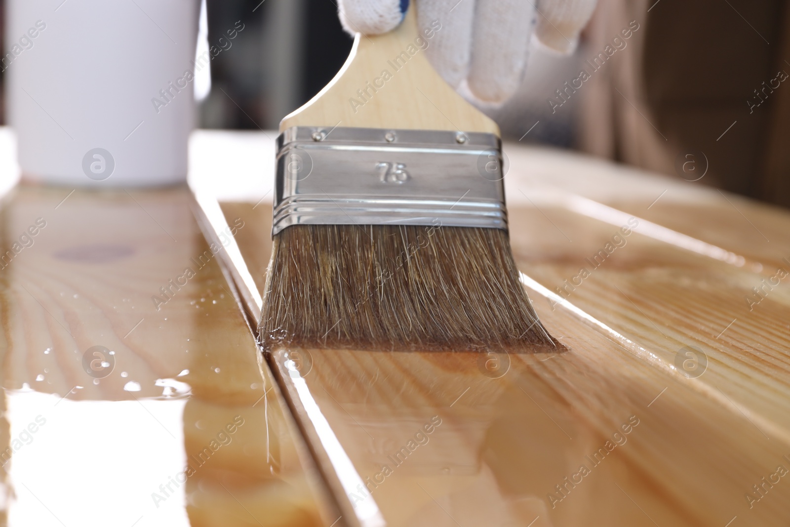 Photo of Man varnishing wooden surface with brush, closeup