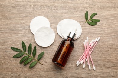 Cotton pads, swabs and makeup removal product on wooden table, flat lay