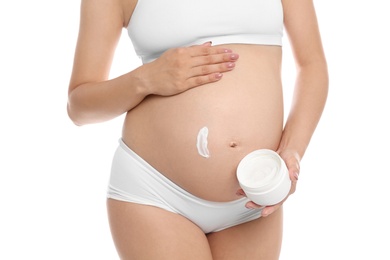 Photo of Pregnant woman applying body cream on belly against white background, closeup