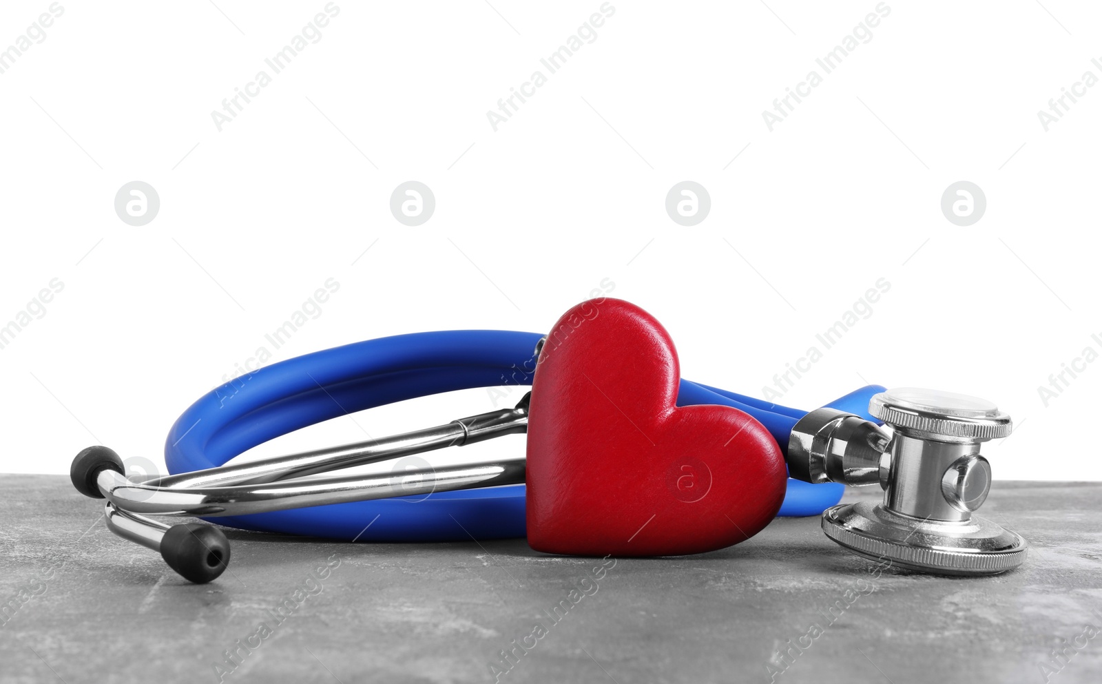 Photo of Stethoscope and red heart on grey table against white background
