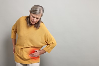 Image of Senior woman suffering from pain in hip on grey background. Space for text