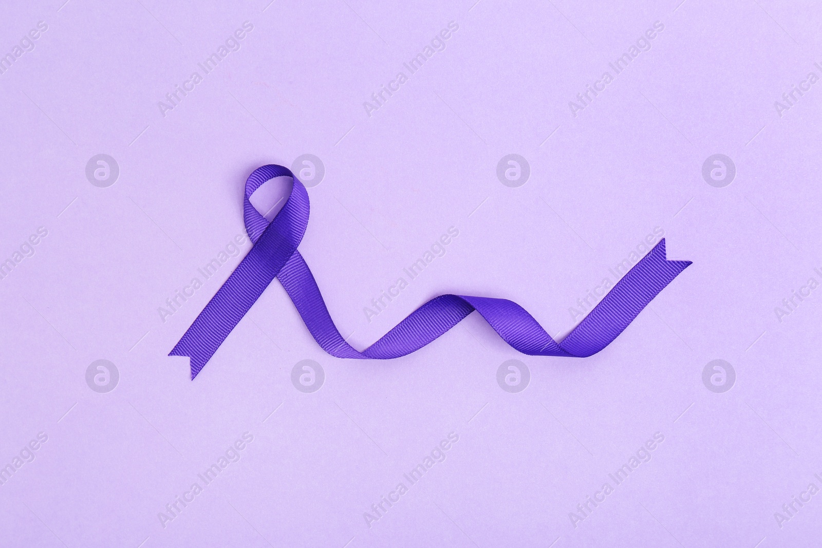 Photo of Purple awareness ribbon on lilac background, top view
