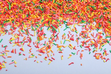 Photo of Colorful sprinkles on light grey background, flat lay. Confectionery decor