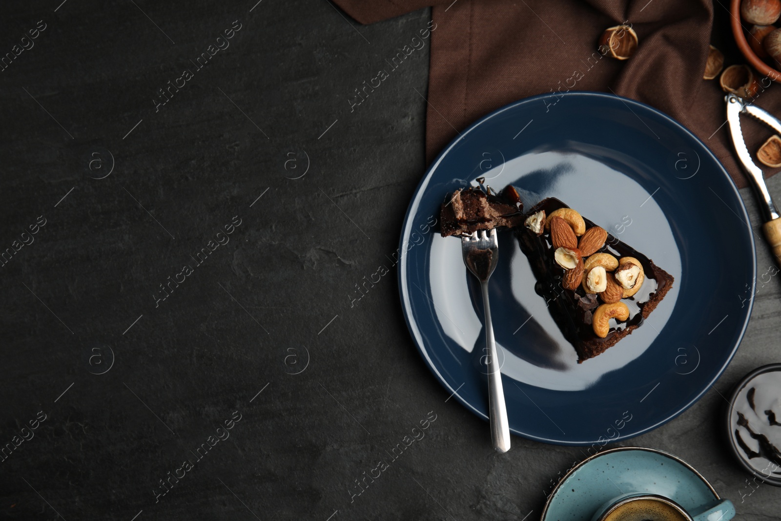 Photo of Piece of tasty homemade chocolate cake with nuts served on black table, flat lay. Space for text