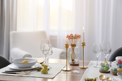 Beautiful Easter table setting with burning candles and floral decor indoors