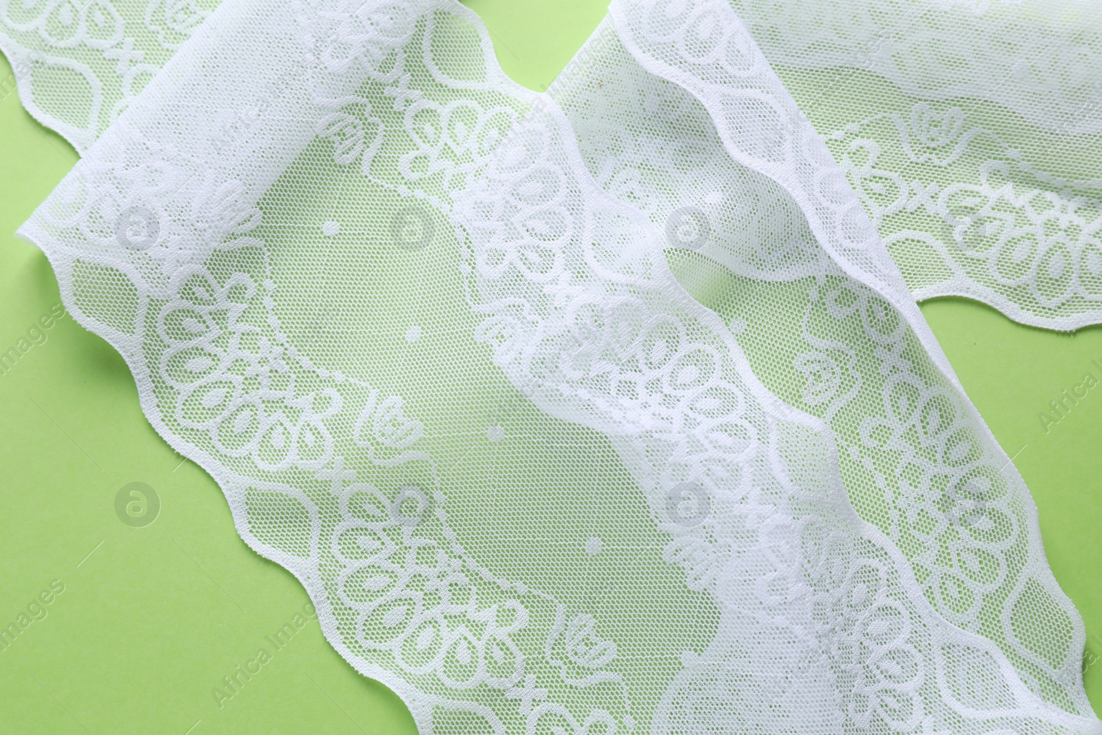 Photo of White lace on green background, top view