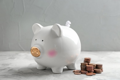 Photo of Piggy bank and coins on table against grey background