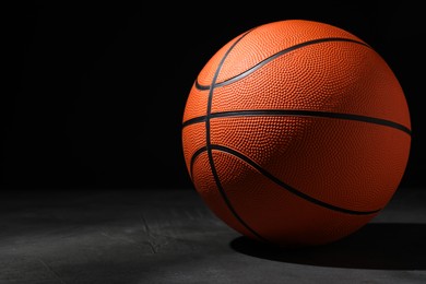 Photo of Basketball ball on grey stone table against dark background, space for text