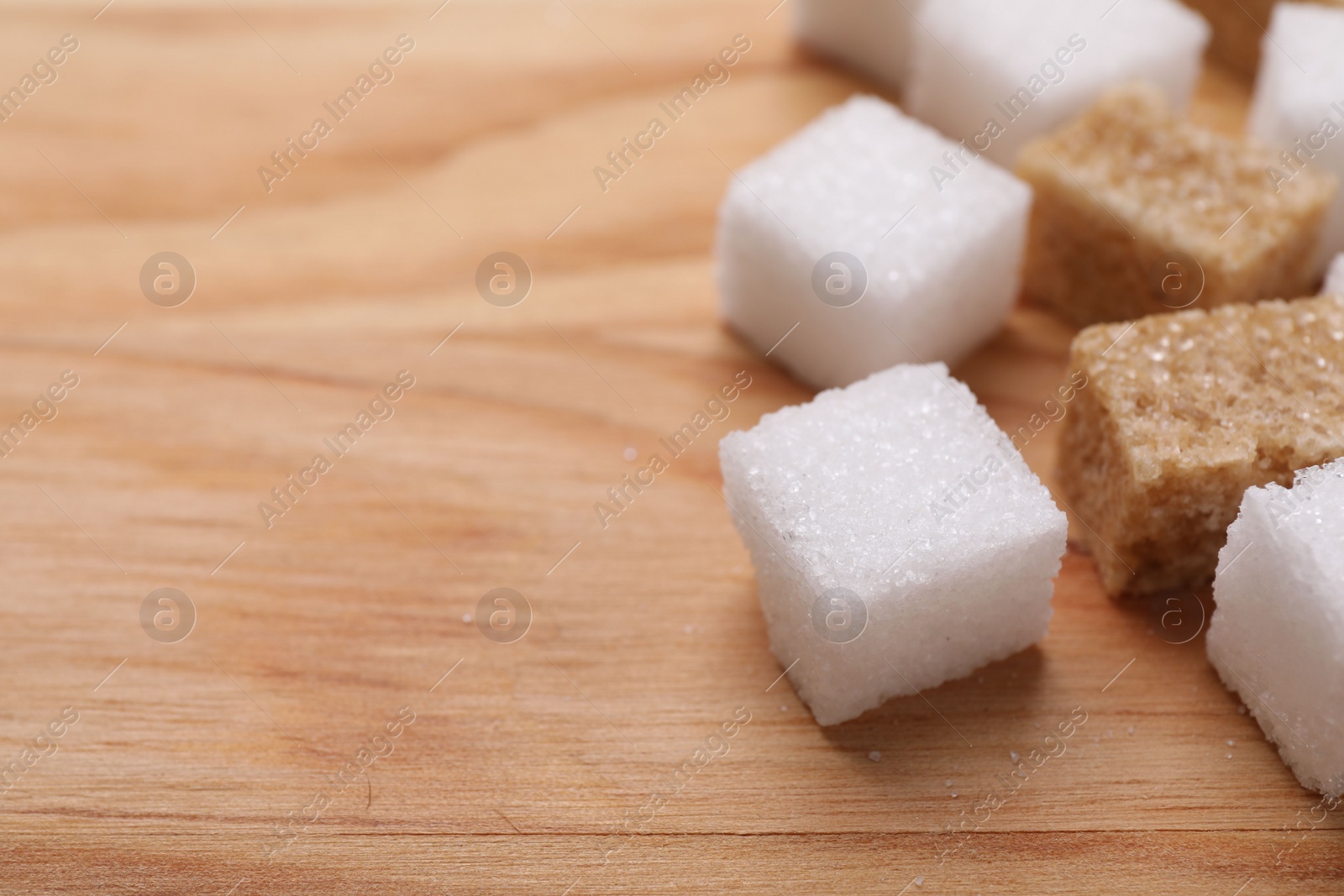 Photo of White and brown sugar cubes on wooden table, closeup. Space for text