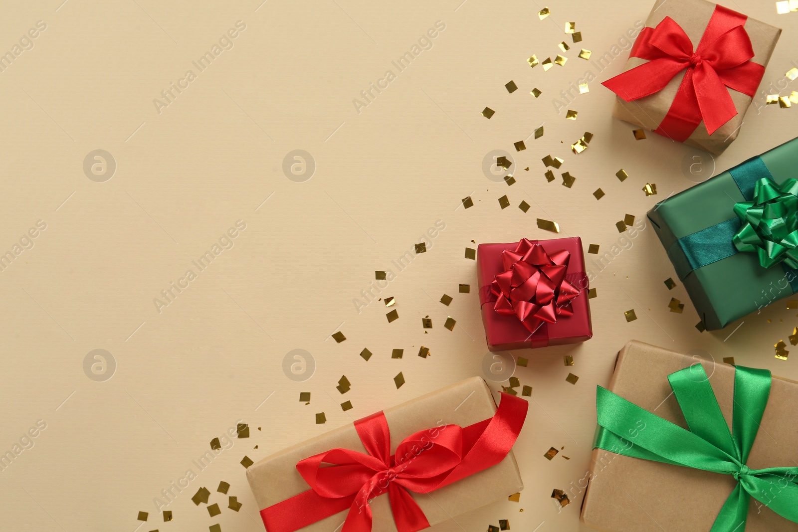 Photo of Gift boxes and shiny confetti on beige background, flat lay. Space for text