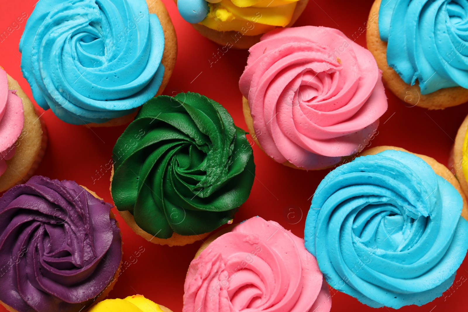 Photo of Delicious cupcakes with bright cream on red background, flat lay