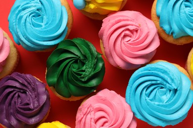 Photo of Delicious cupcakes with bright cream on red background, flat lay