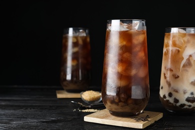 Photo of Tasty brown milk bubble tea on black wooden table. Space for text