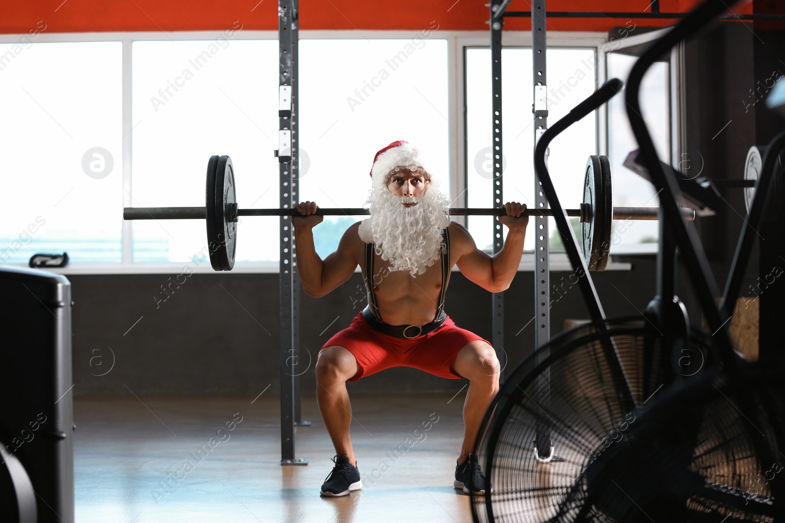 Photo of Young muscular man in Santa costume training at gym