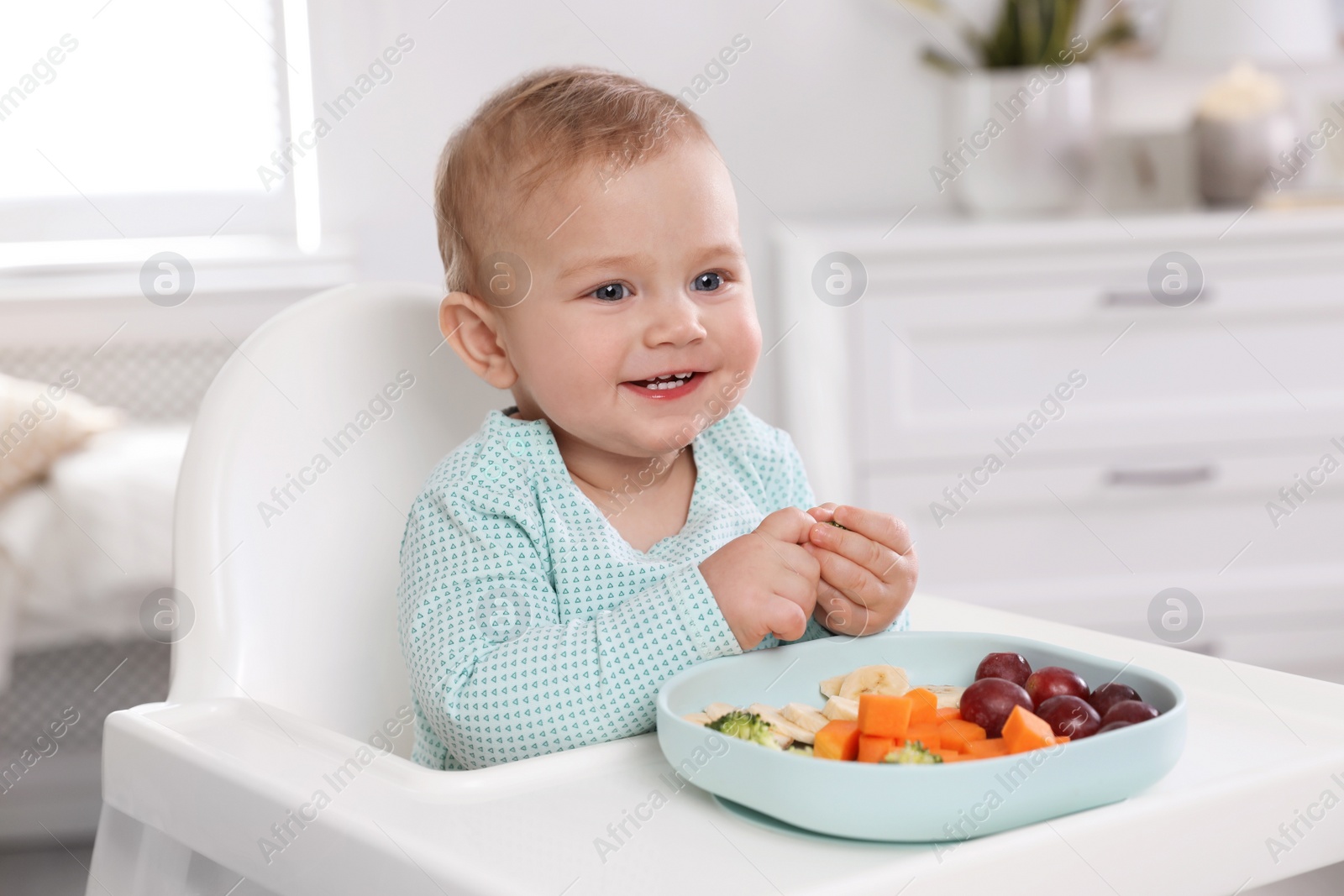 Photo of Cute little baby in high chair at home