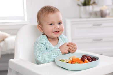 Cute little baby in high chair at home