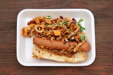 Photo of Fresh delicious hot dog on wooden table, top view