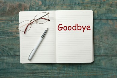 Image of Notebook with word Goodbye on wooden table, top view