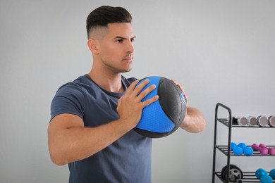 Photo of Muscular man exercising with medicine ball in modern gym