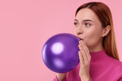 Photo of Woman inflating purple balloon on pink background, space for text