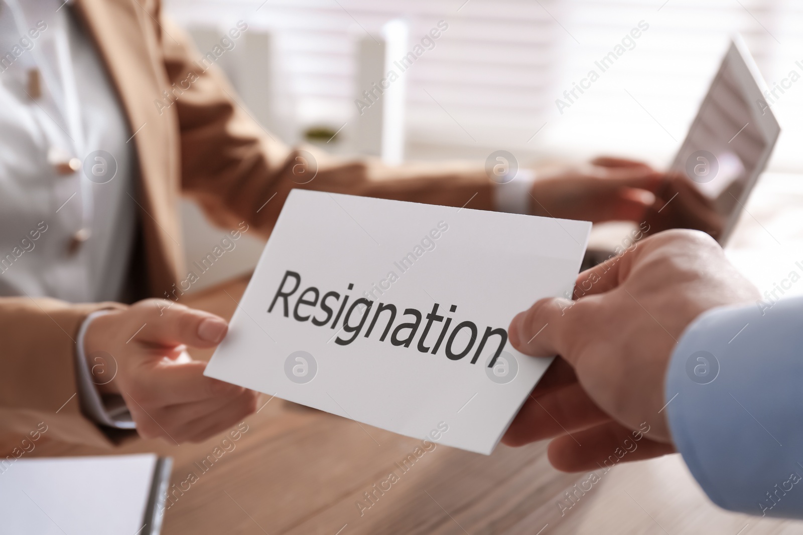 Photo of Employee giving resignation letter to boss in office, closeup