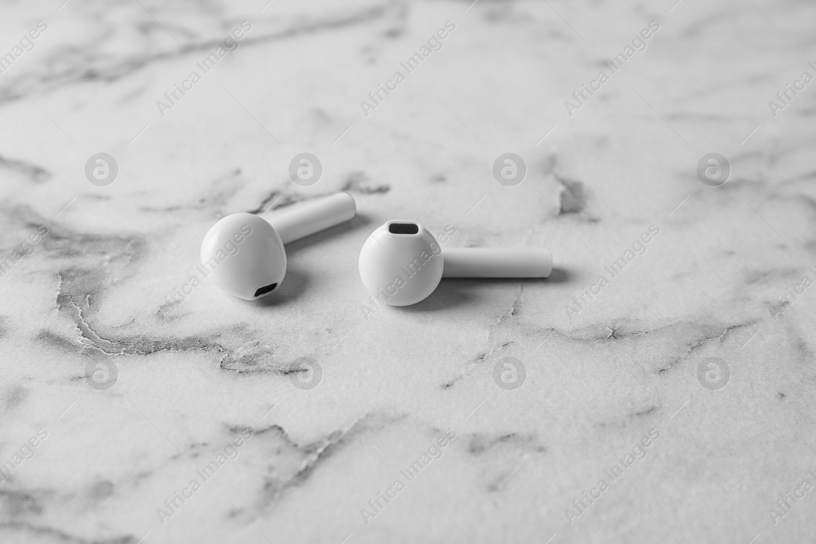 Photo of Pair of modern wireless earphones on marble table