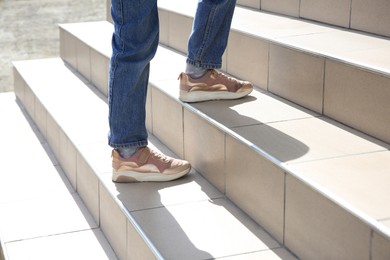 Woman walking up beige stairs on sunny day, closeup