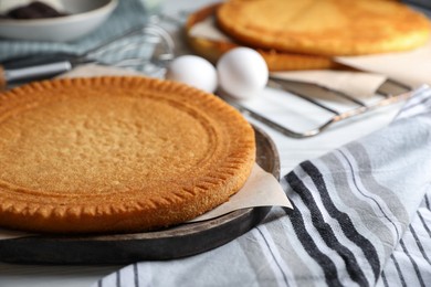 Photo of Delicious homemade sponge cake and ingredients on white table, closeup