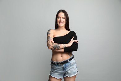 Photo of Beautiful woman with tattoos on body against grey background