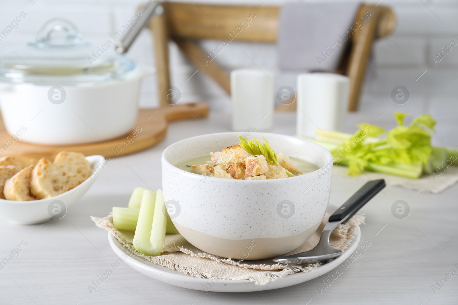 Photo of Bowl of delicious celery soup served on white table