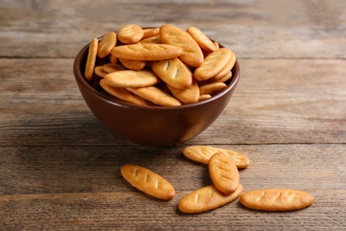 Photo of Delicious crispy crackers in bowl on wooden table