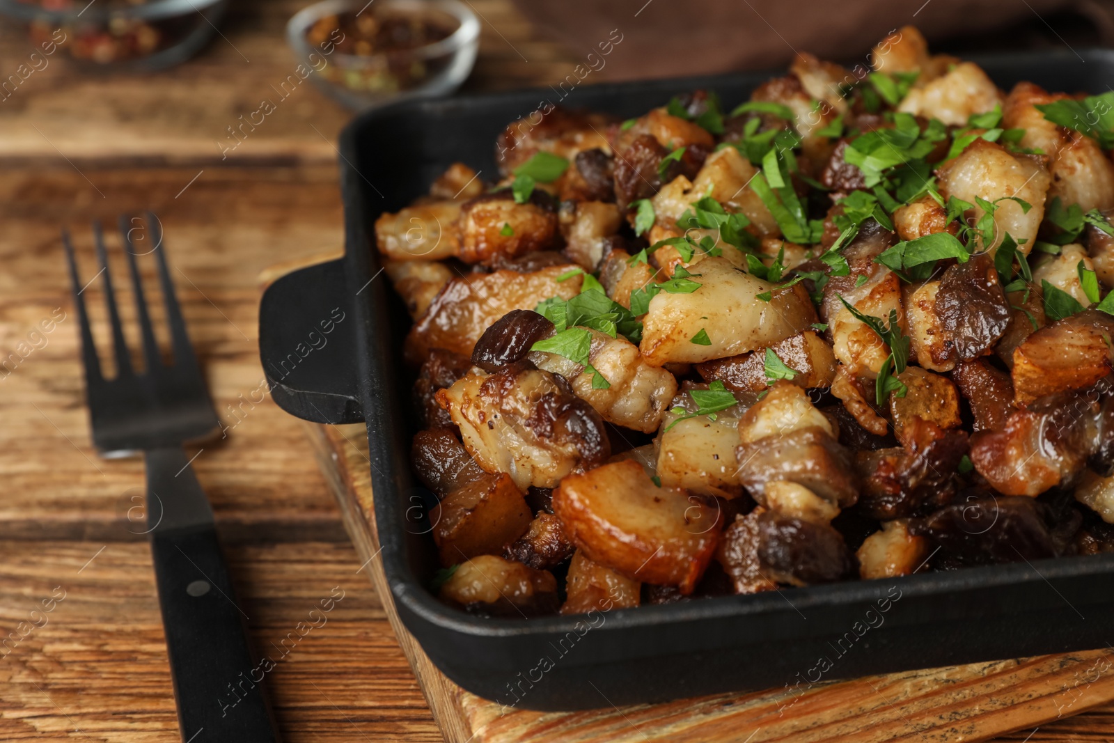 Photo of Tasty fried cracklings on wooden table, closeup. Cooked pork lard