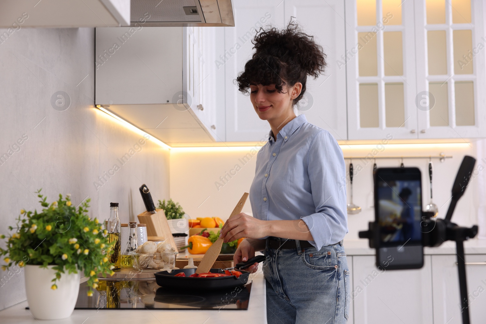 Photo of Food blogger cooking while recording video in kitchen