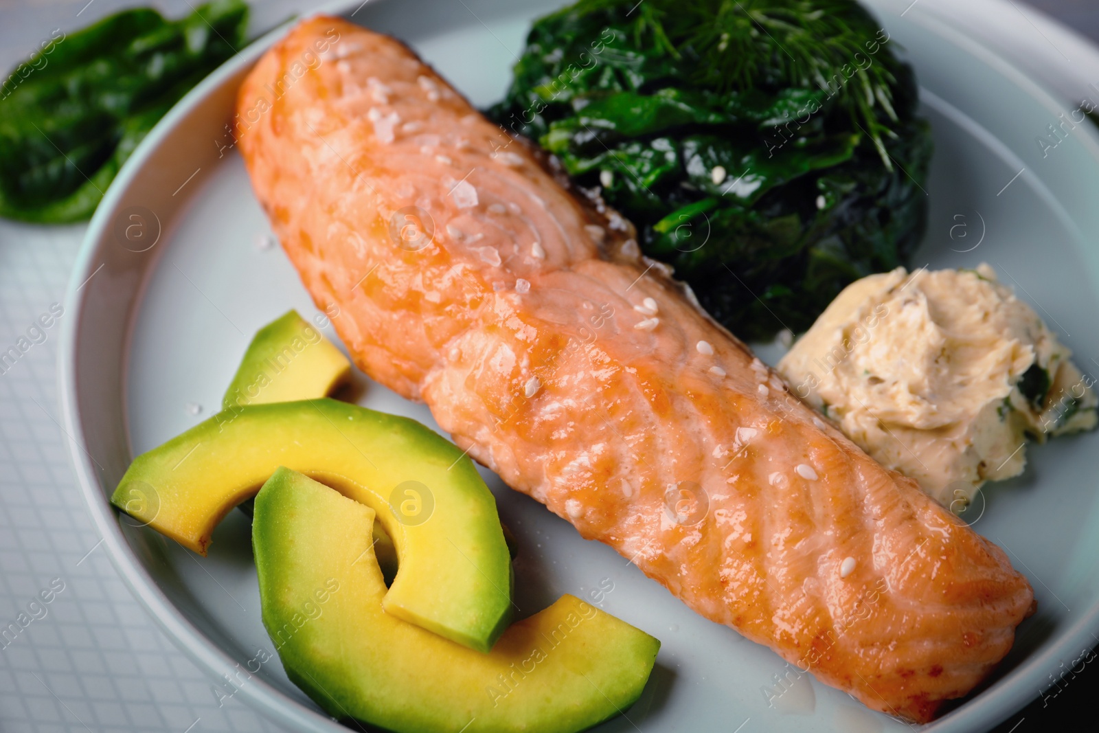 Image of Tasty salmon with spinach and avocado on plate, closeup. Food photography  