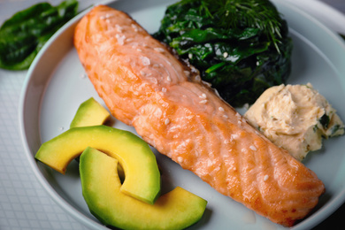 Tasty salmon with spinach and avocado on plate, closeup. Food photography  