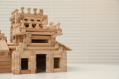 Wooden castle on white table, space for text. Children's toy