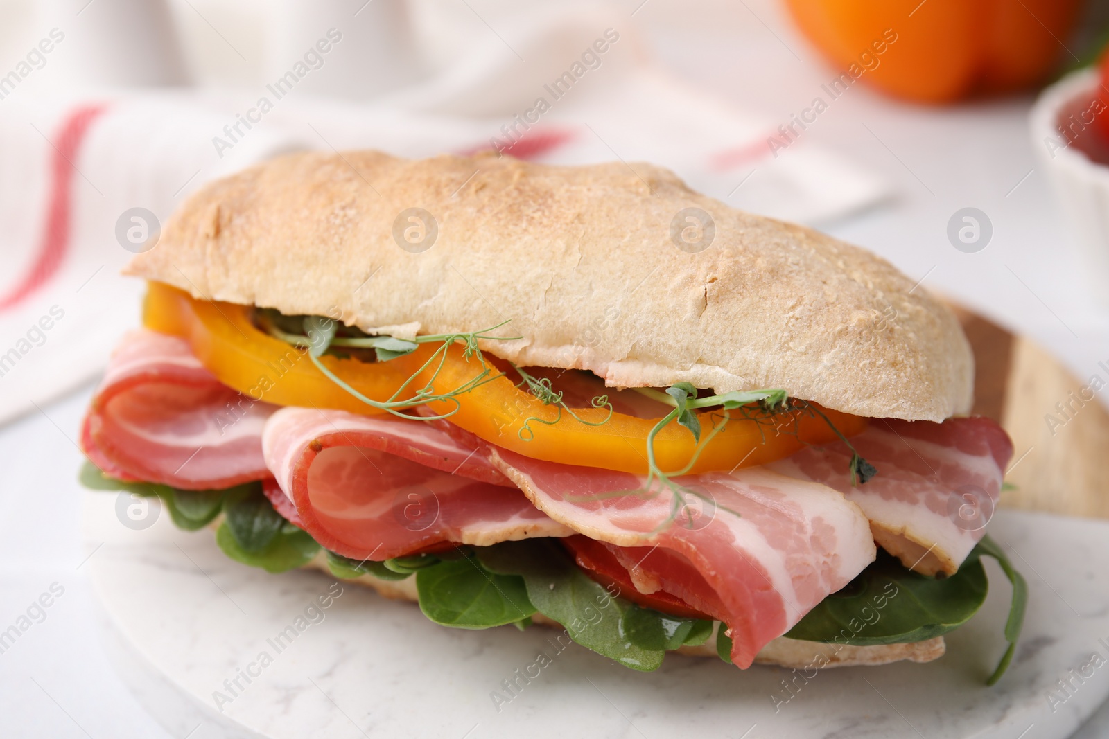 Photo of Tasty sandwich with bacon and bell pepper on white table, closeup