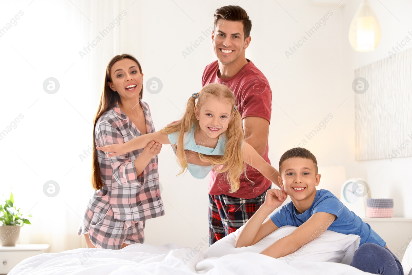 Photo of Happy young family with children having fun in bedroom