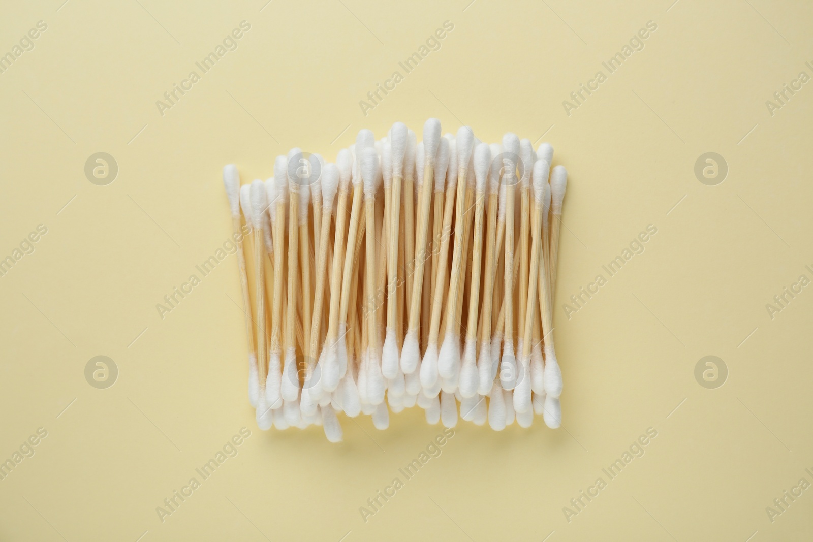 Photo of Many wooden cotton buds on beige background, flat lay