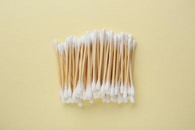 Many wooden cotton buds on beige background, flat lay