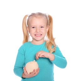 Little girl putting money into piggy bank on white background