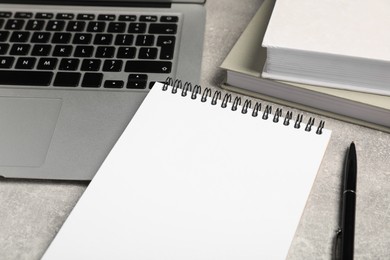 Photo of Empty notebook, laptop, books and pen on light grey table